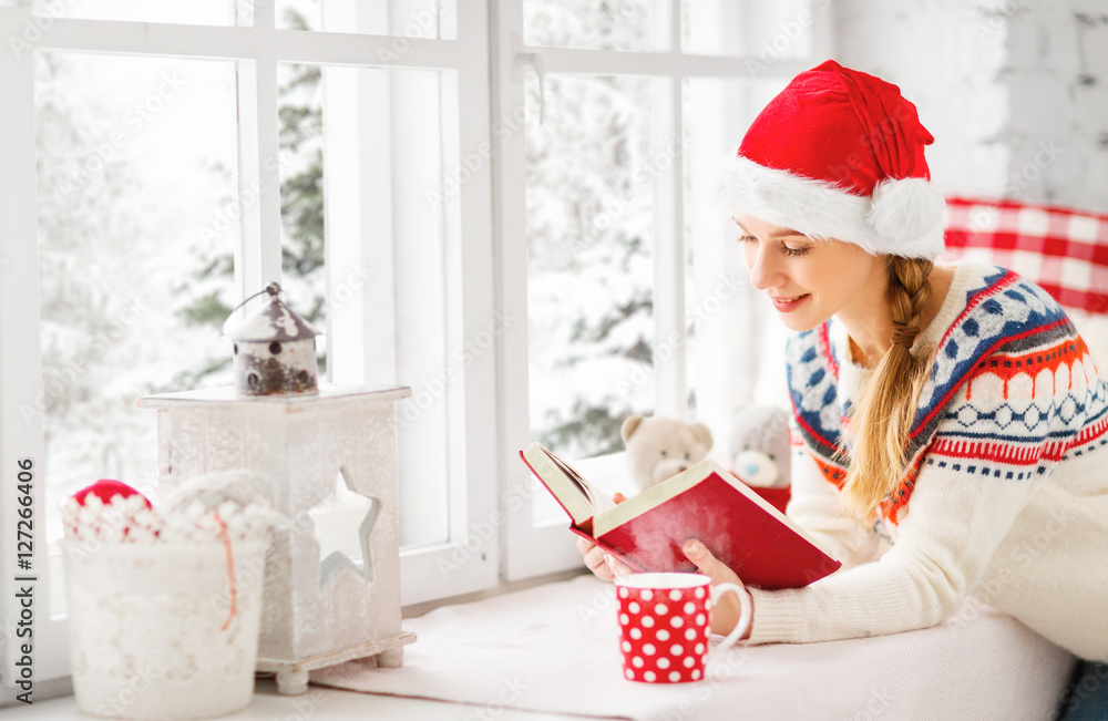 快乐的年轻女人，在冬窗喝一杯热茶，看书