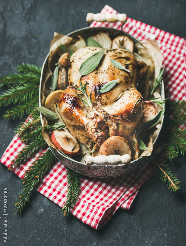 烤箱烤整只鸡，配洋葱、苹果和鼠尾草，托盘上有圣诞餐桌装饰