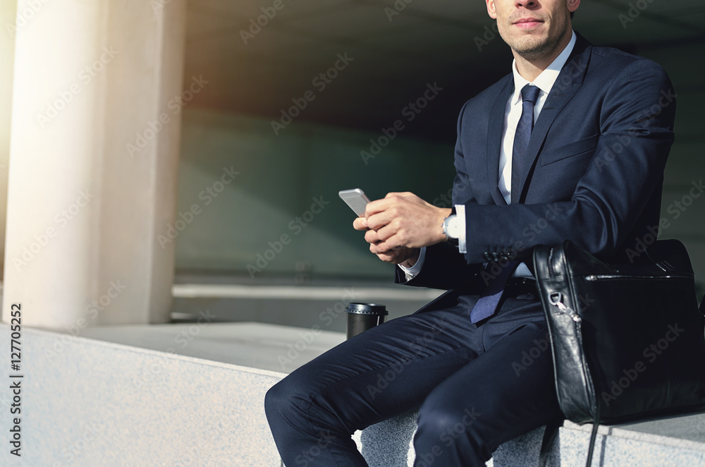 一名身穿西装的男子拿着一部灰色手机