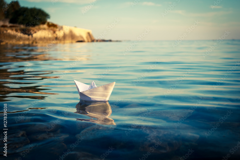 纸船漂浮在海上。折纸船航行。美丽的波浪波纹背景。Unusu