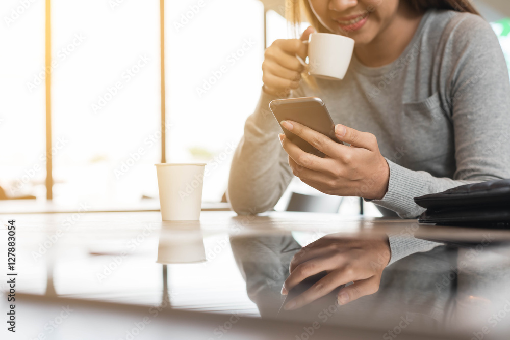 一名女子在咖啡店使用智能手机，图像反射在g上