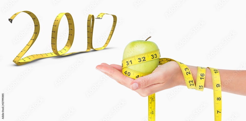 Composite image of woman holding an apple with tape measure 