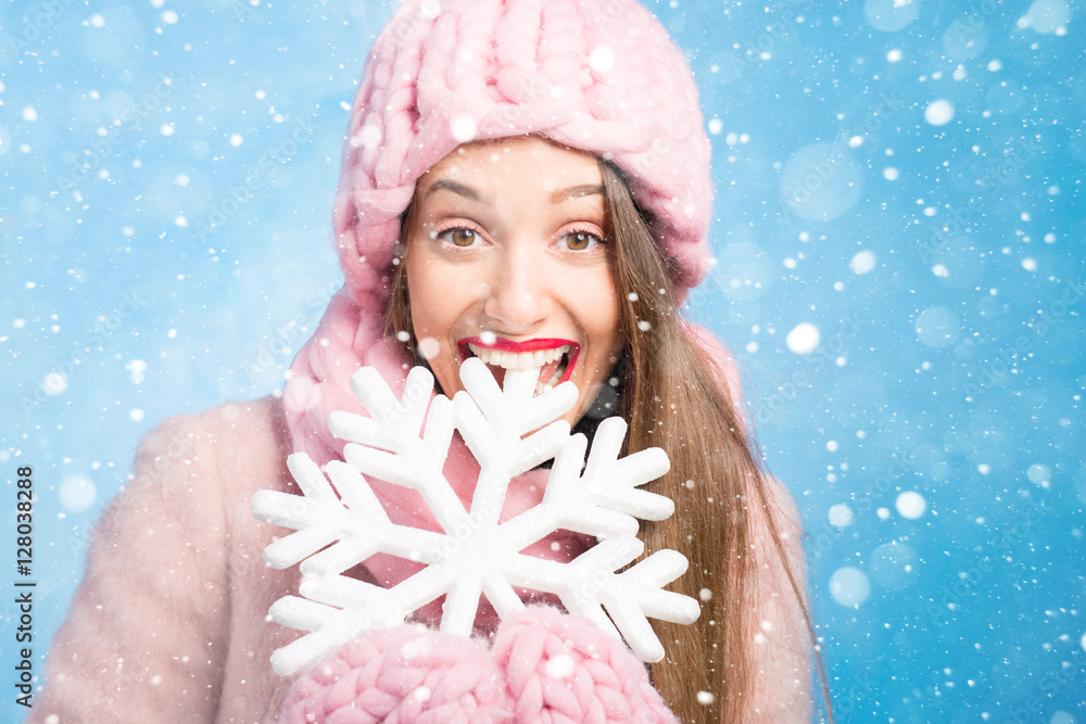 一位穿着针织粉色皮屑、手套和帽子的美女的冬季肖像，帽子上有雪花