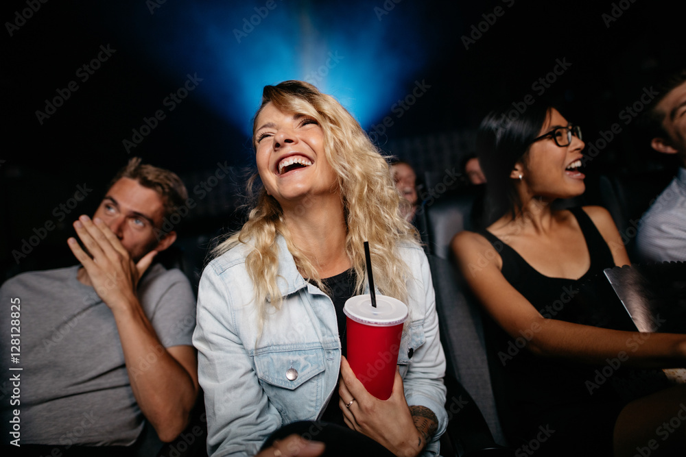 微笑的年轻女人在剧院里看女人