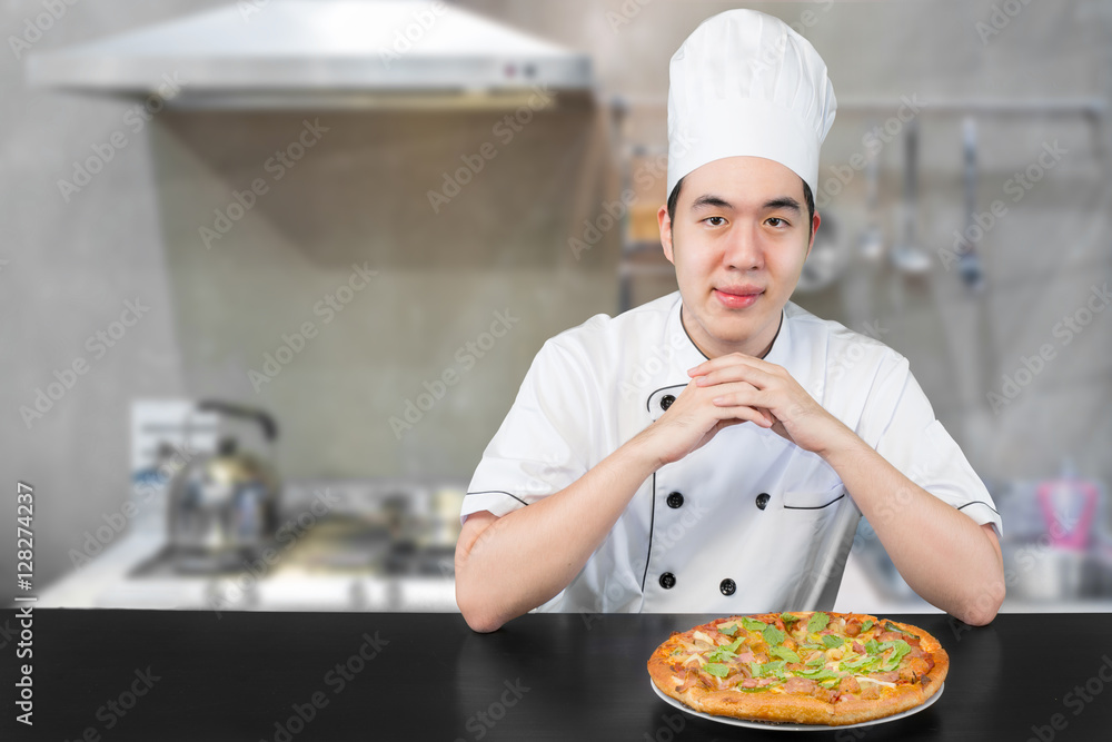 身穿白色制服的亚洲青年首领为您提供美味的披萨。