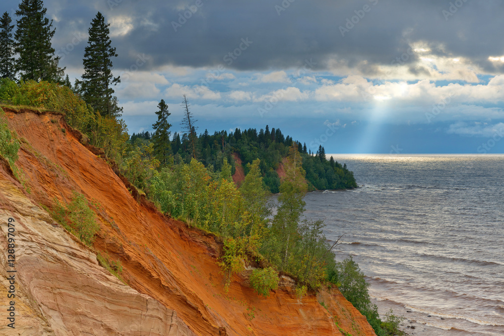 Нigh steep coast of Lake Onega at sunset during a storm.