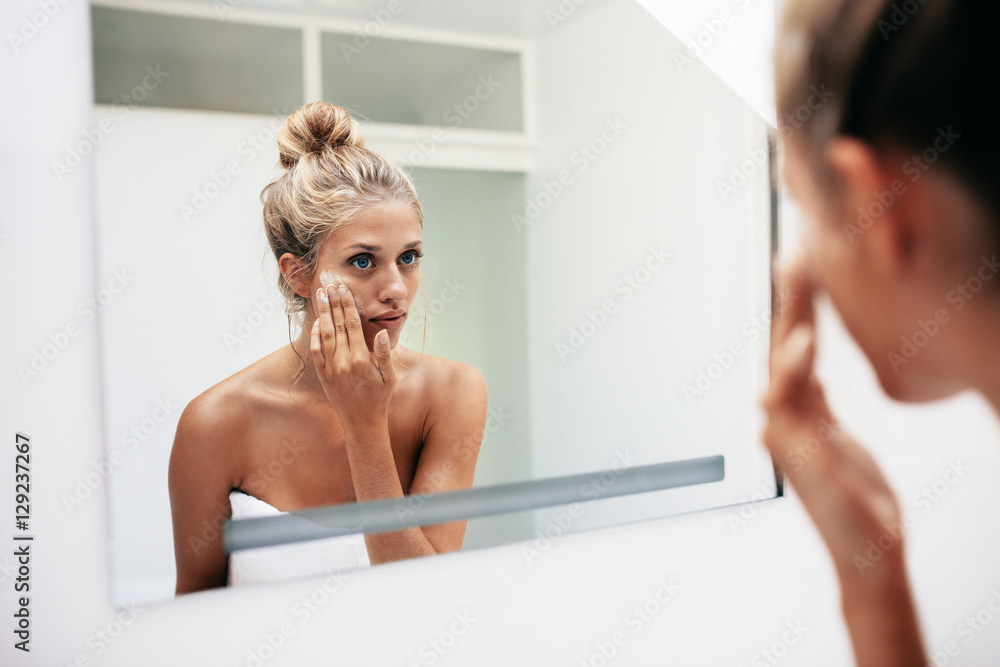 女性在面部皮肤上涂抹保湿霜