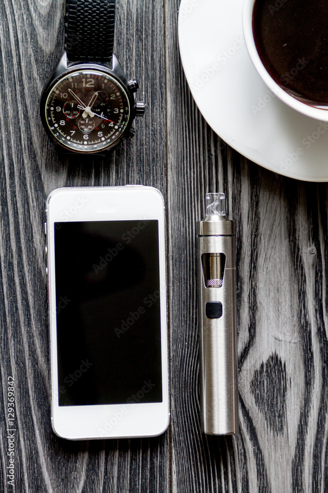咖啡、电子烟、男士配饰深色木质背景俯视图