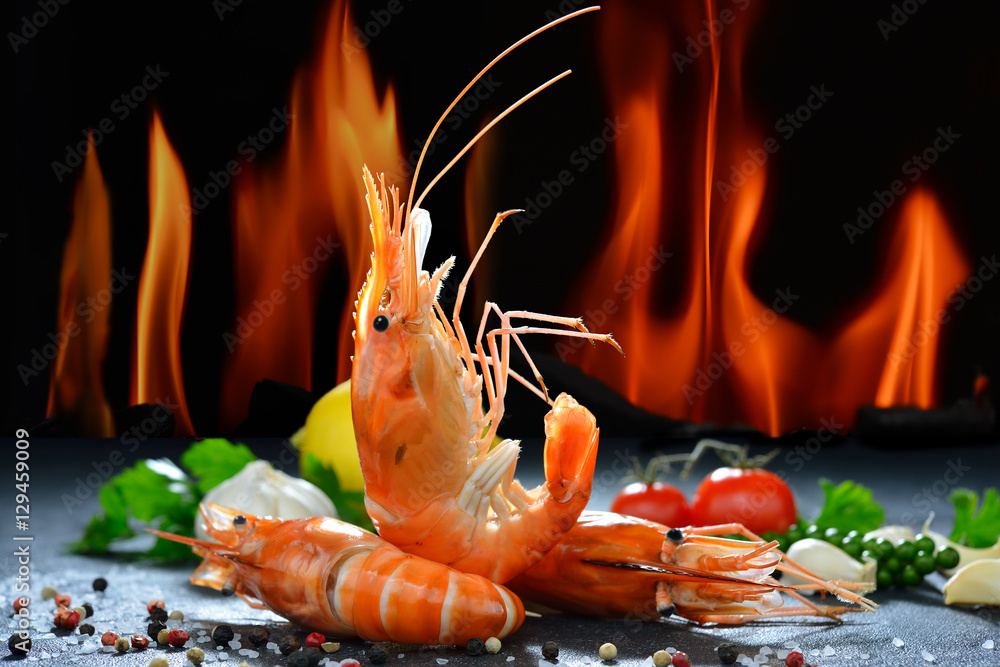 煮熟的虾，火焰背景上有调味料的大虾