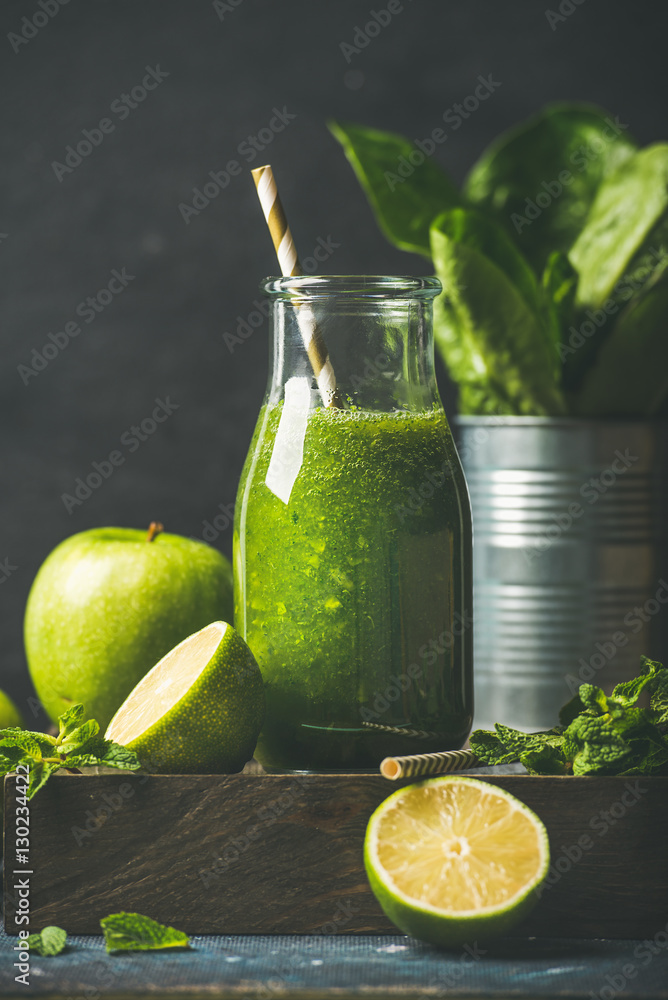 Green smoothie in glass bottle with apple, romaine lettuce, lime and mint, dark background, selectiv