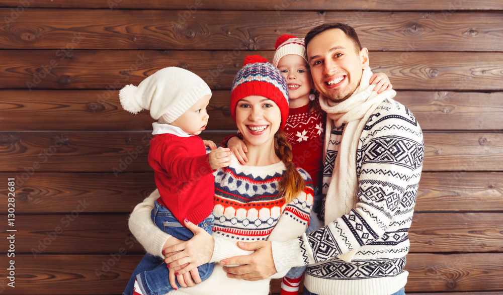 happy family mother, father and children in winter hats on woode