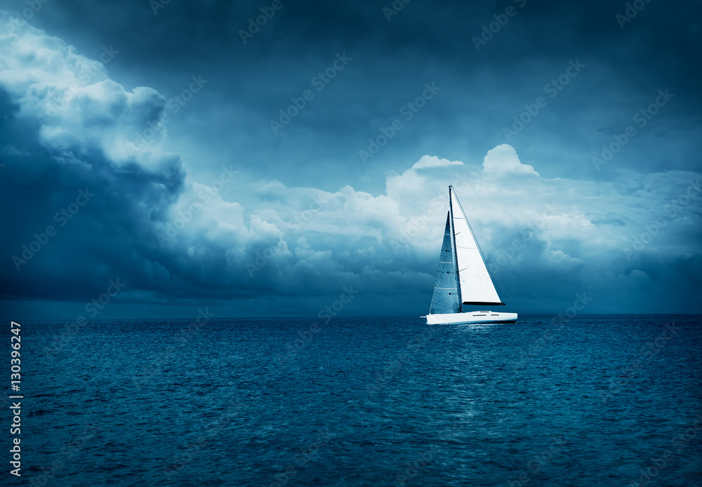 白色游艇在风暴海中航行。黑暗的雷电之夜背景。戏剧性的风暴云景。危险