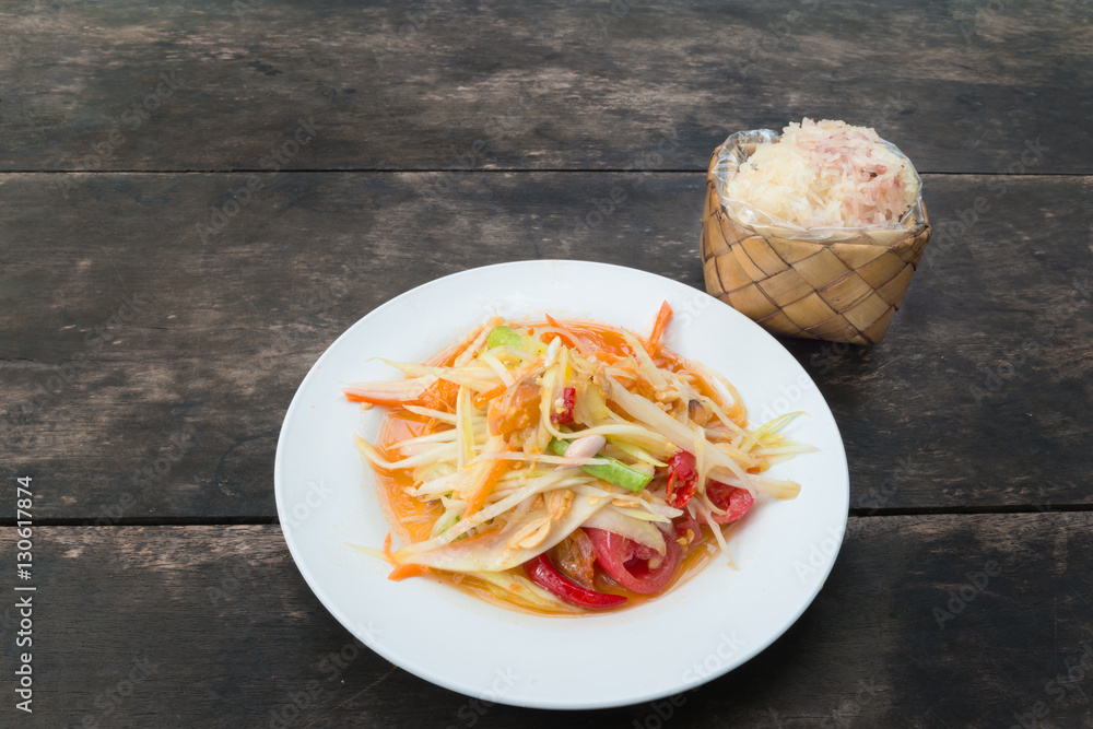 Som tam thai or Green papaya salad with sticky rice in bamboo co