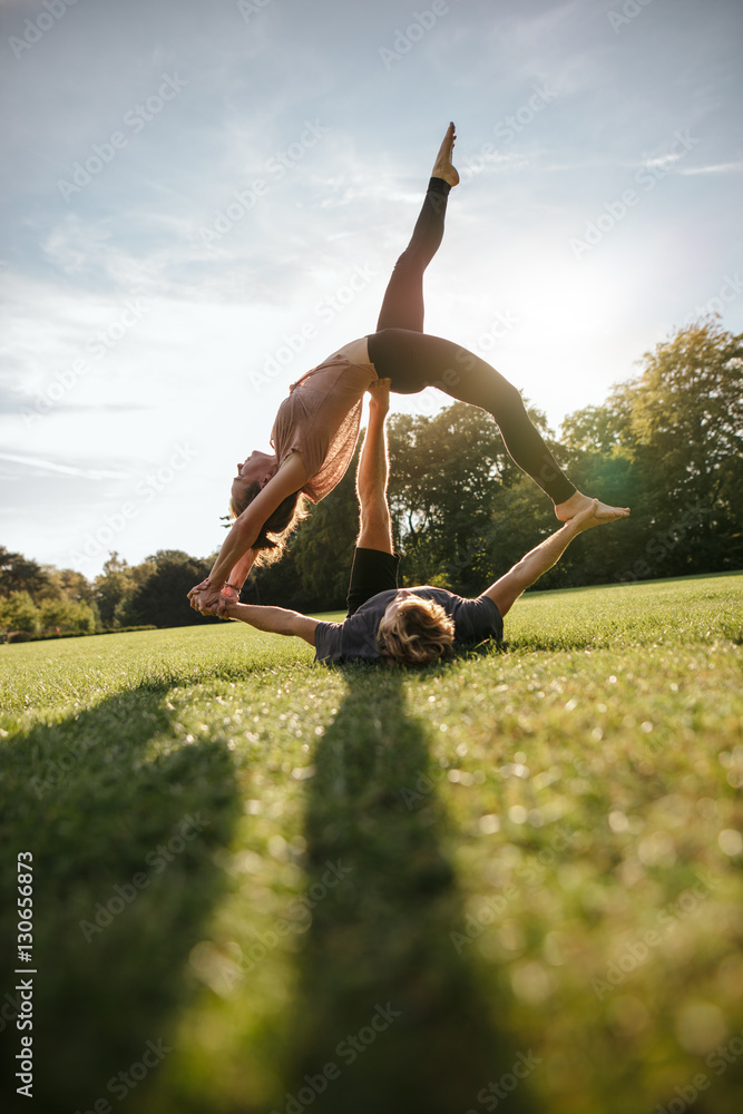Couple doing acrobatic yoga on grass