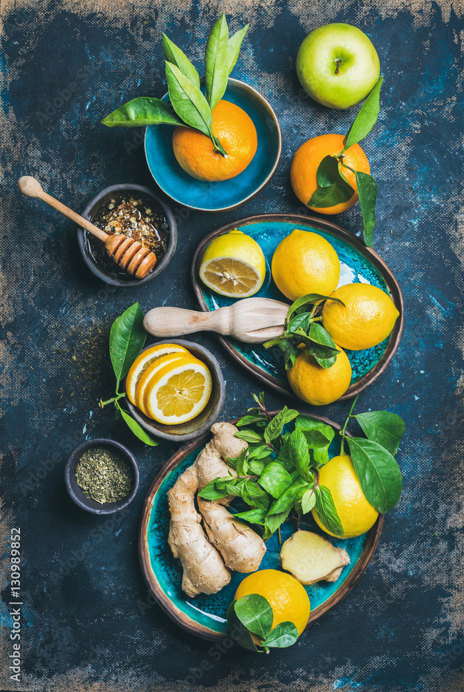 Oranges in blue ceramic bowls , mint, ginger, honey, apple and spices over dark blue plywood backgro