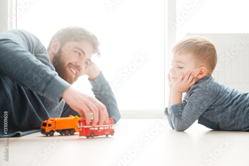 Boy playing on the floor with his bearded father.