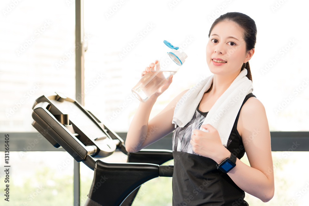 Beautiful asian woman rest holding water bottle after treadmill