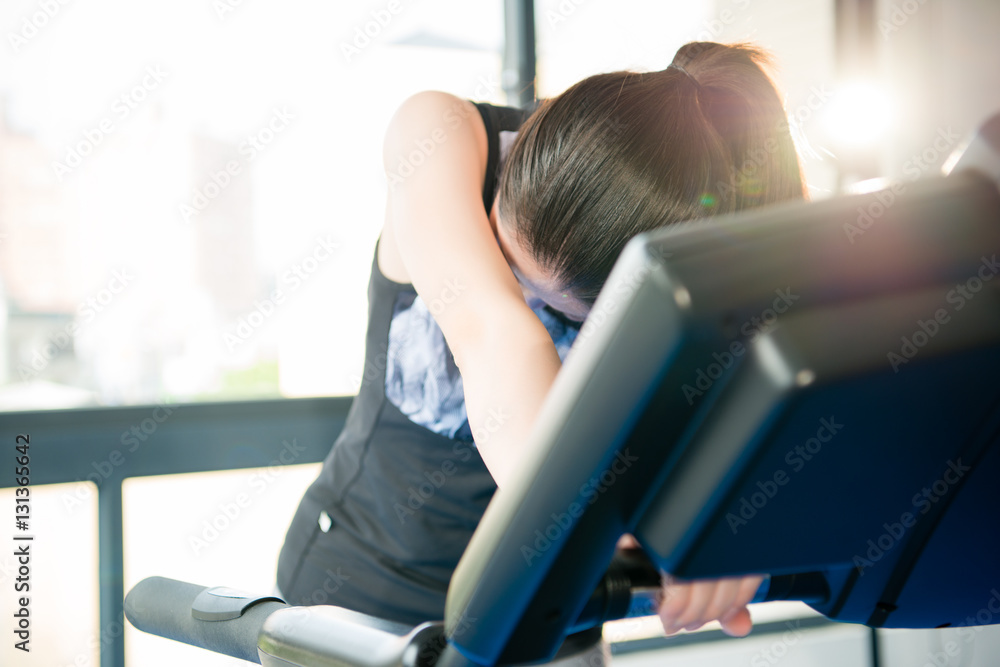 运动型亚洲女性在跑步机上跑步出汗并感到疲劳
