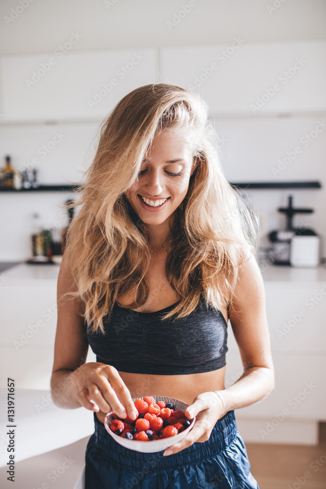 厨房里吃浆果的快乐年轻女性