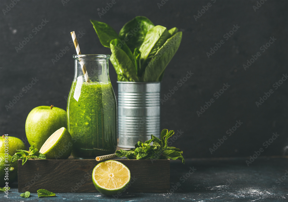 Green smoothie in bottle with apple, romaine lettuce, lime and mint, dark background, selective focu