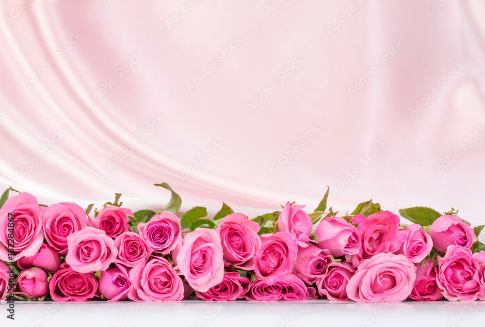 柔软的白色丝绸面料上的一束甜美的粉红色玫瑰花瓣，