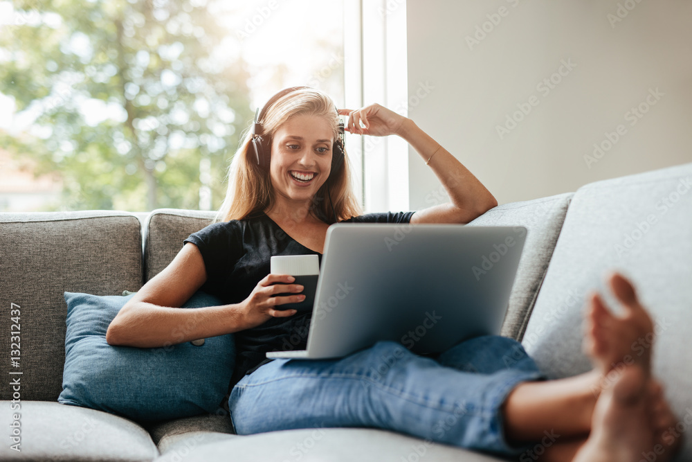 微笑的女人拿着笔记本电脑在客厅放松