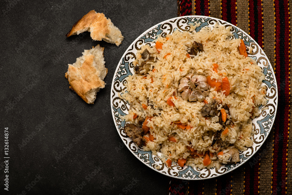Pilaf on plate with oriental ornament and Traditional Asian breads - churek. Plov. Top view.