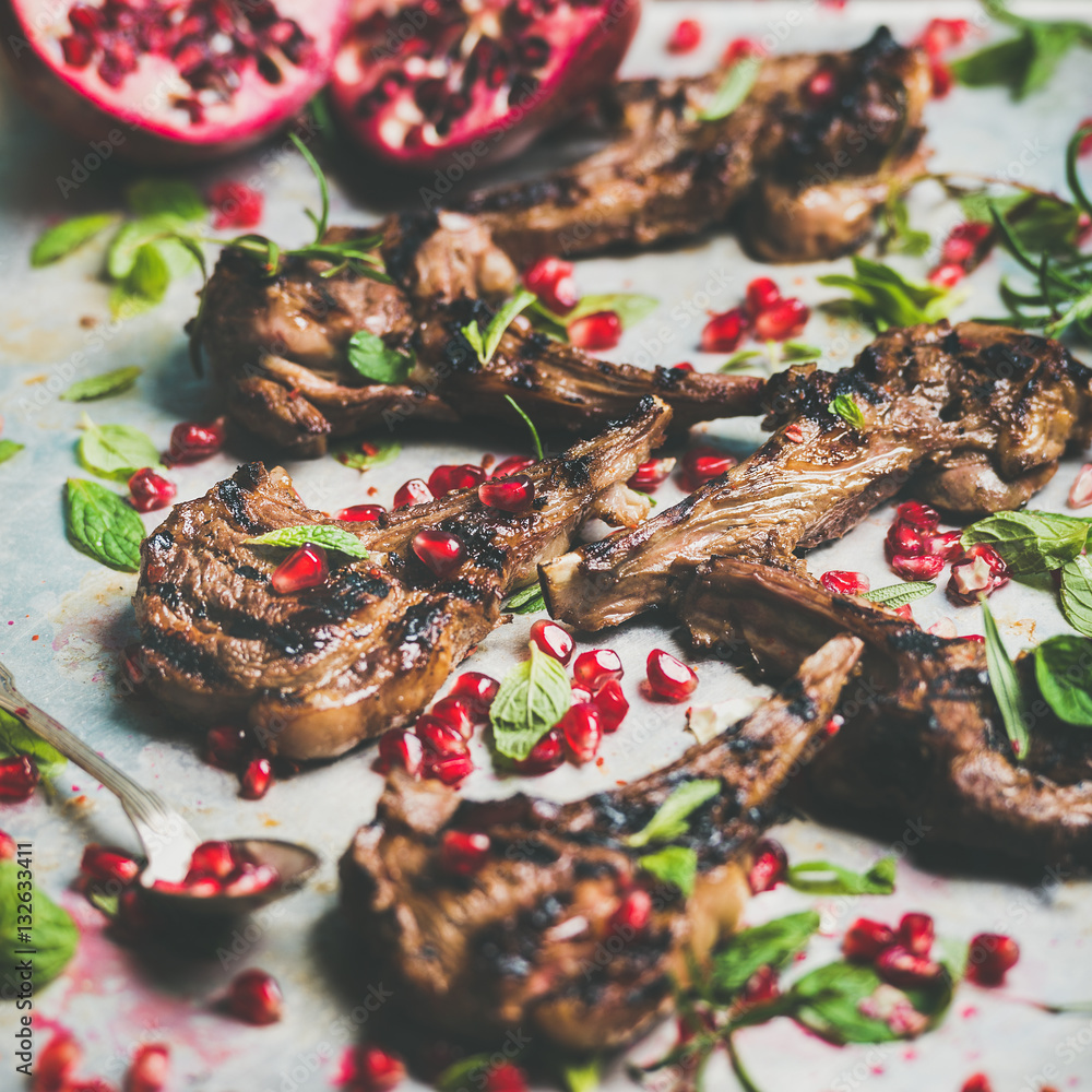 Grilled lamb ribs with pomegranate seeds, fresh mint and rosemary in metal baking tray. Meat barbecu