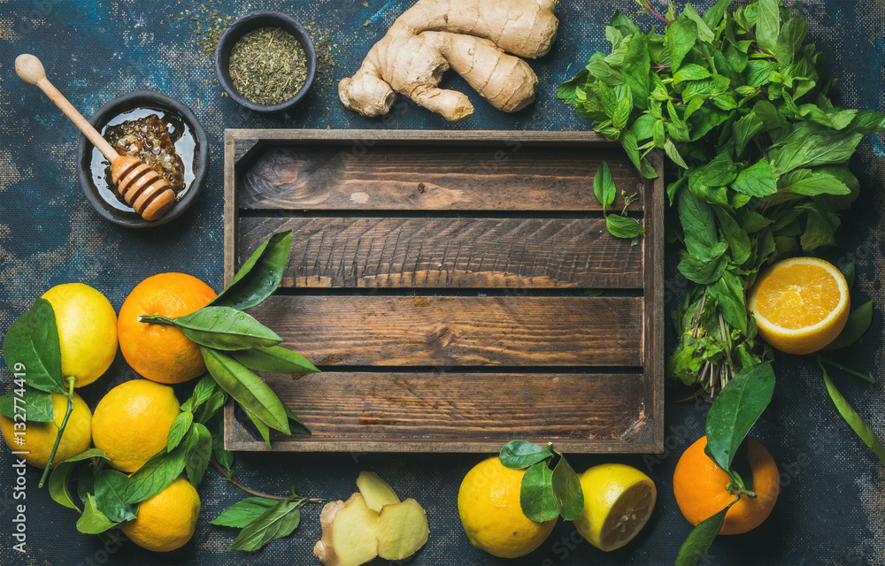 Ingredients for making natural hot drink with wooden tray in center. Oranges, mint, lemons, ginger, 