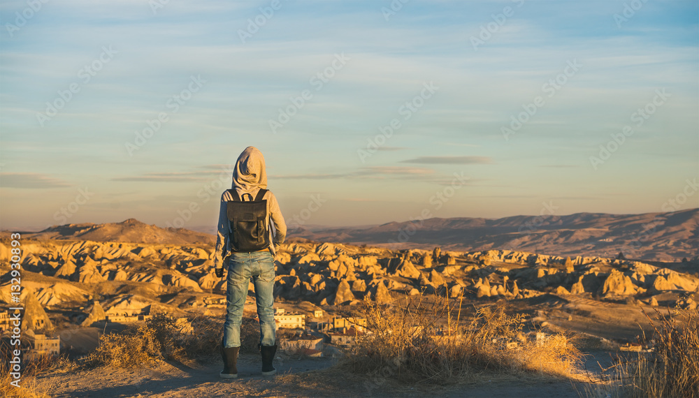 Young woman traveller wearing hoodie, backpack and jeans watching sunrise in the mountains over Gore