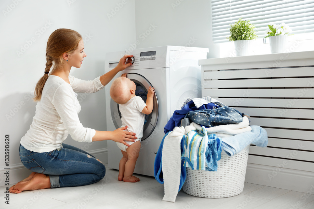 mother housewife with baby engaged in laundry fold clothes into