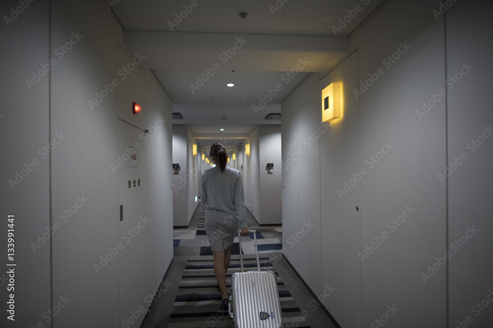 Women are walking through the hotel corridor with a suitcase