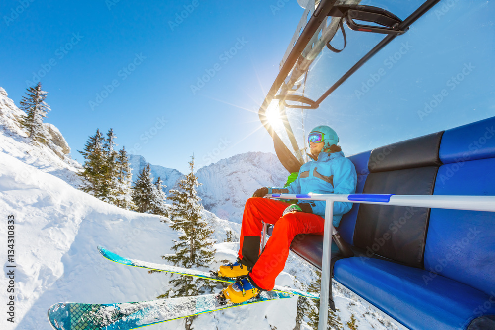 Skier sitting at ski chair lift in Alpine mountains