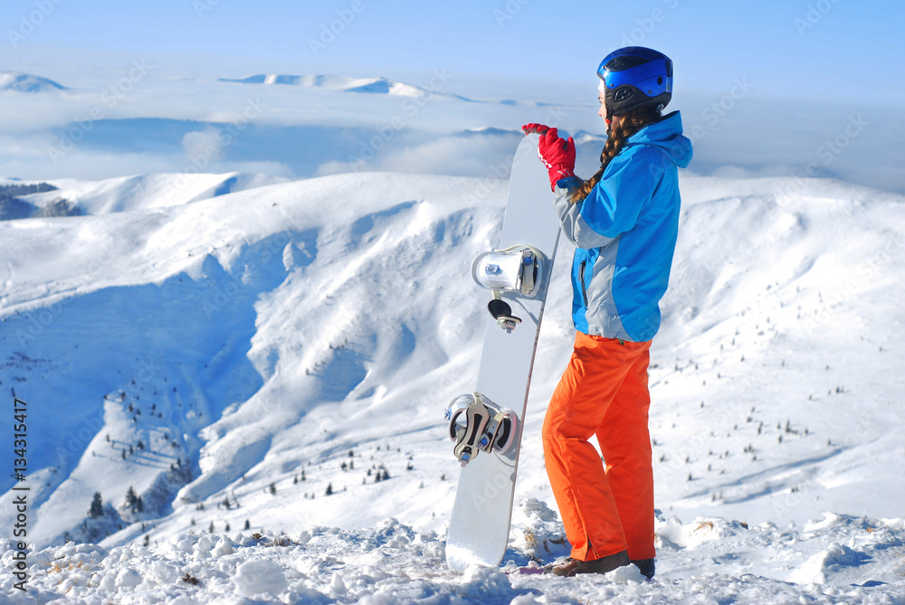 女孩站在山顶上，手里拿着滑雪板