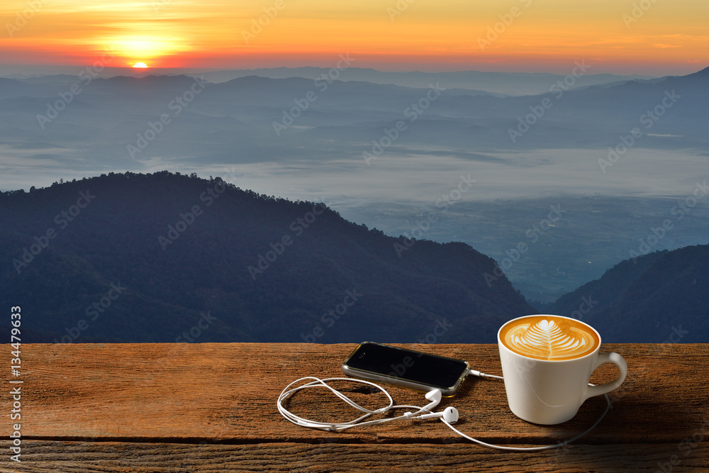 Morning cup of coffee latte with mountain background at sunrise