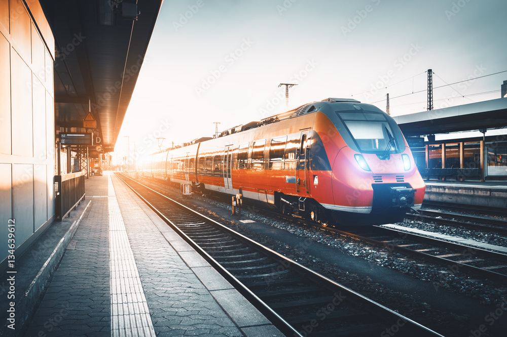 日落时分，现代高速红色通勤列车在火车站。打开列车前灯。