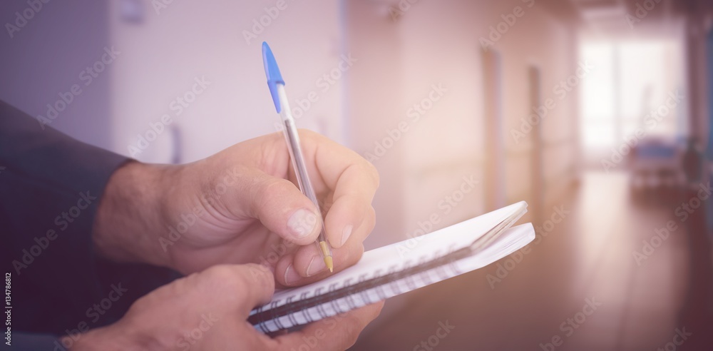 Composite image of close up of man writing in spiral book