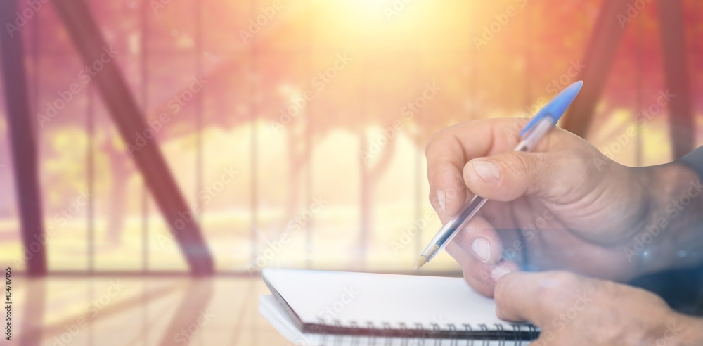 Composite image of close up of man writing in notepad