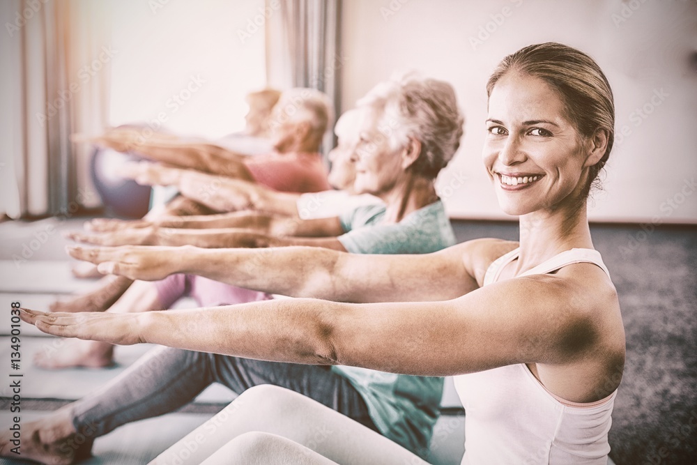 Portrait of Instructor performing yoga with seniors