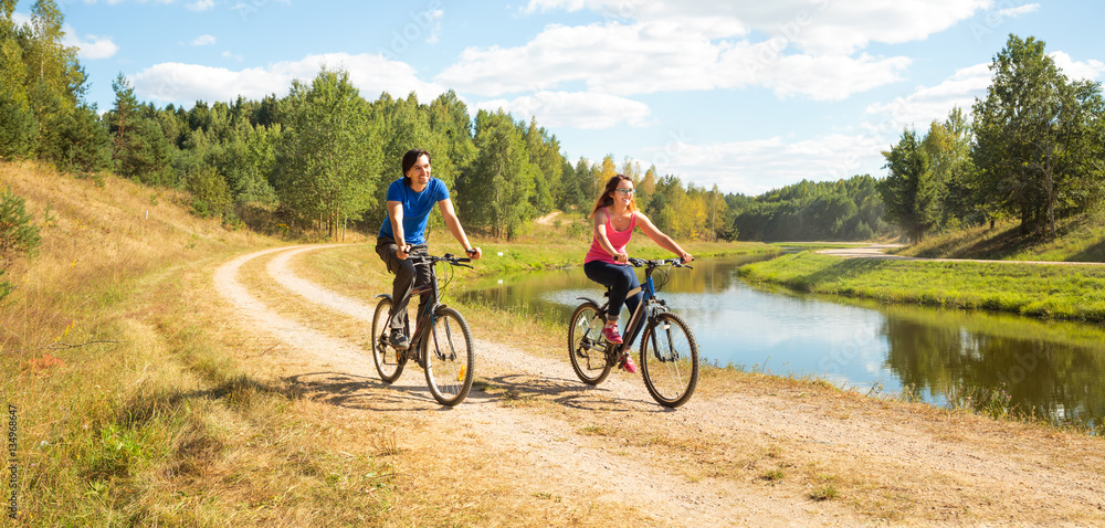 Young Happy Couple Riding Bicycles by the River. Healthy Lifestyle Concept. 