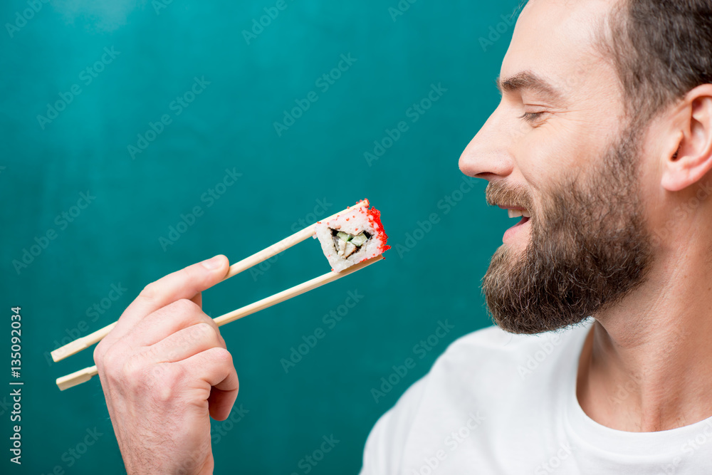 Man eating sushi with chopsticks on the green background