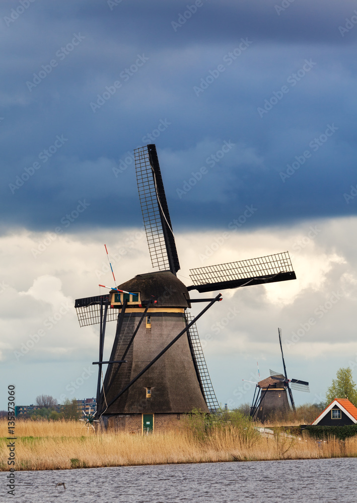 Windmills against cloudy sky at sunset in famous Kinderdijk, Netherlands. Rustic landscape with trad