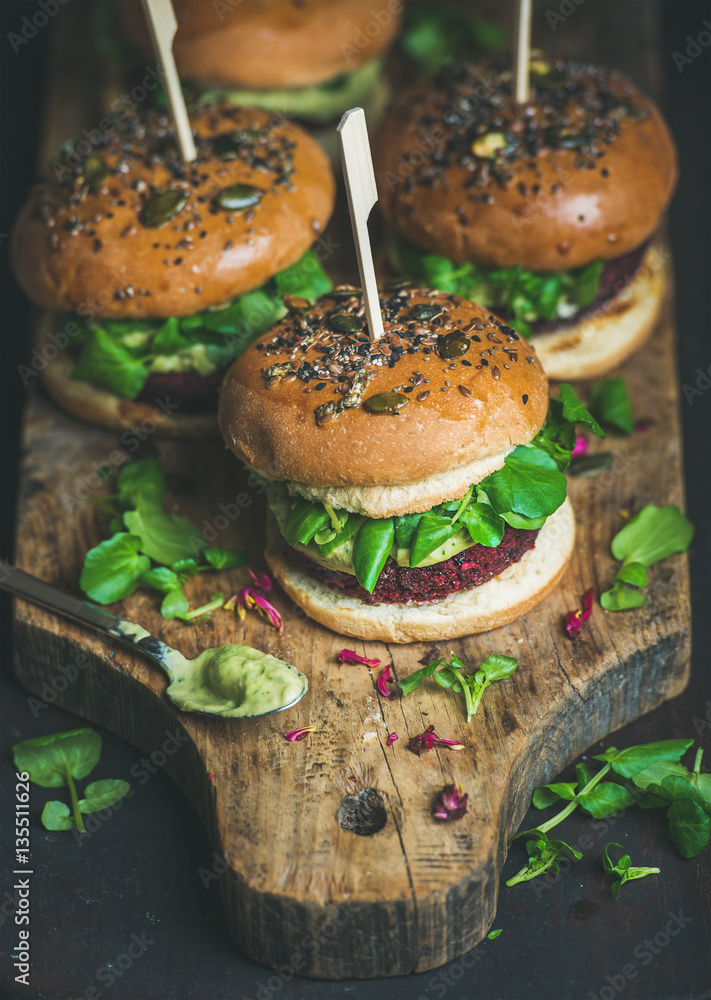 Healthy vegan burger with beetroot and quinoa patty, arugula, avocado sauce, wholegrain bun on rusti