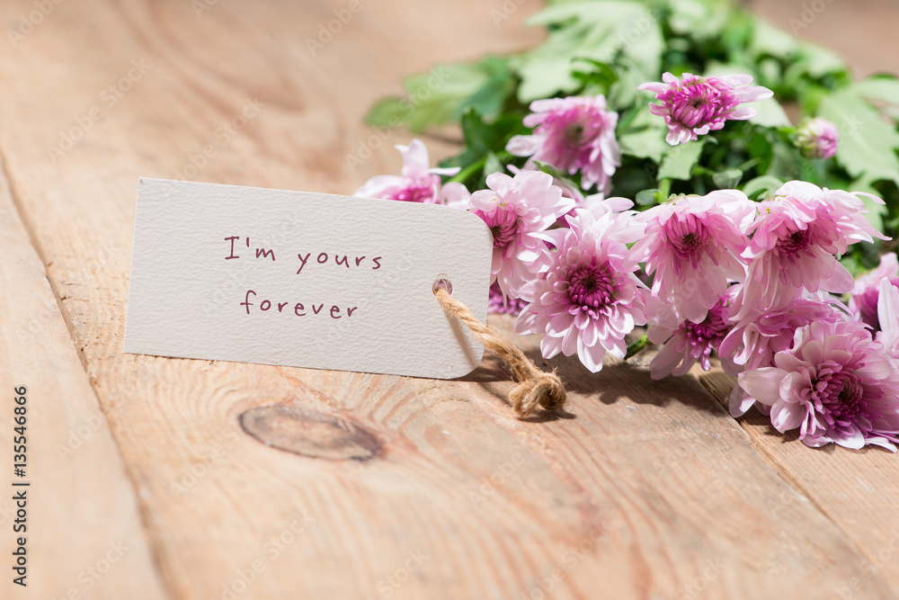Valentines Day. Paper tag and pink flowers on wooden table.