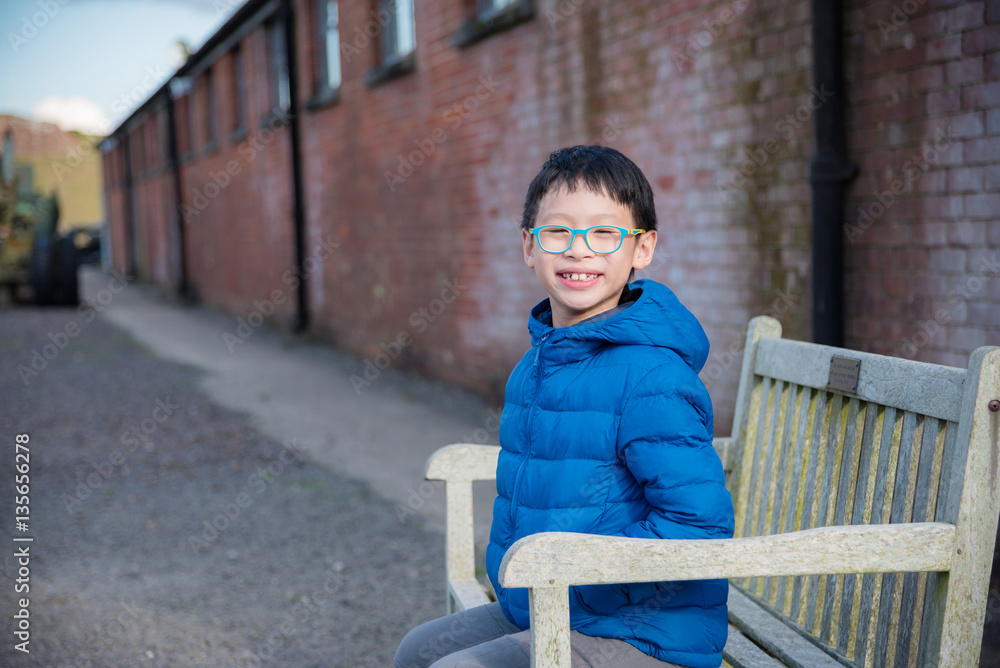 Young asian boy sits on the old or vintage wood chair and brick