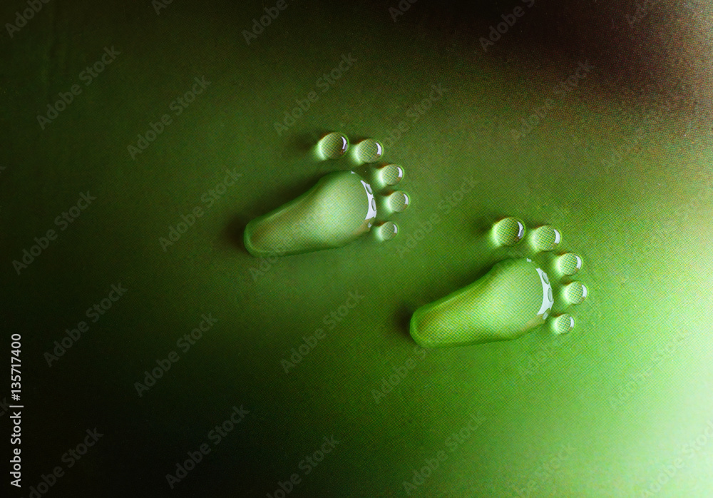 绿色背景特写微距上的水滴留下脚的痕迹。水滴以o的形式滴落露水