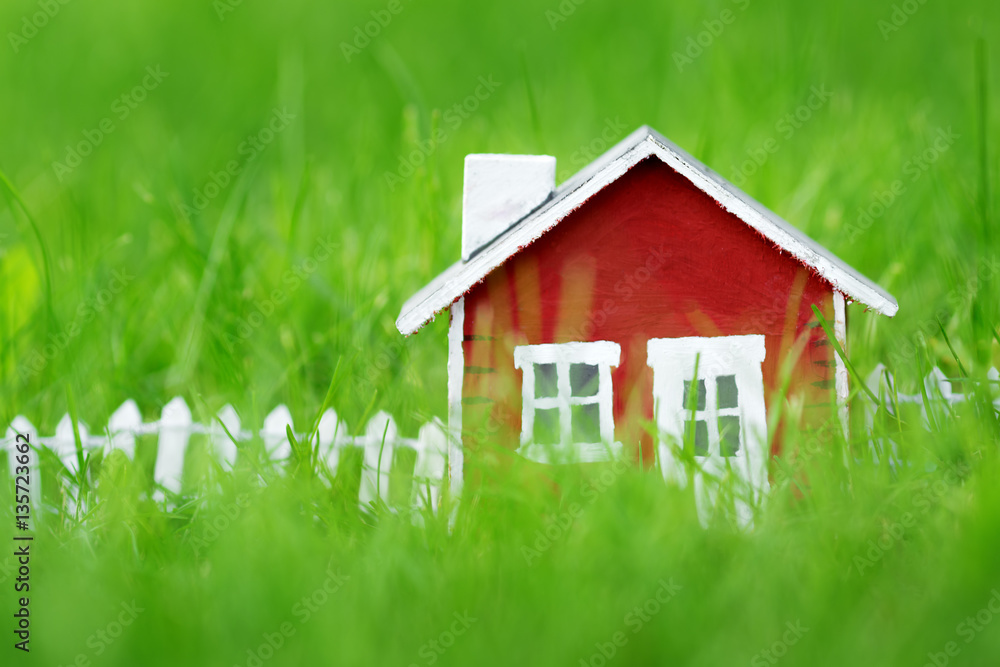 red wooden house model on the grass in garden