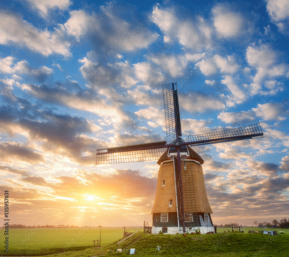 Windmill at sunrise in Netherlands. Beautiful old dutch windmill against colorful sky with clouds in