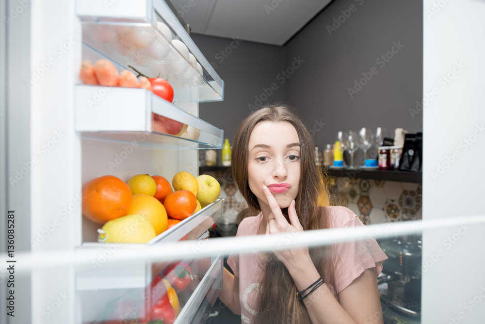 Woman taking food from the refrigerator. View from the inside