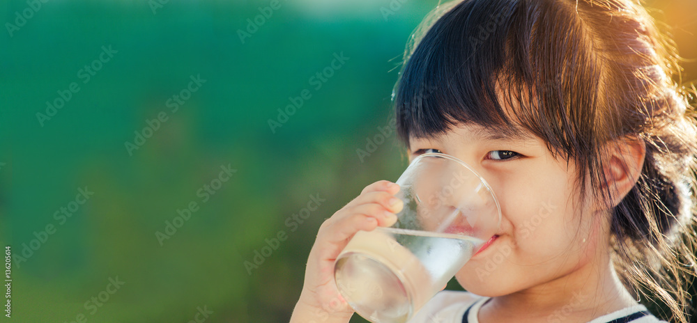 Girl holding glass with water. Happy child at summer